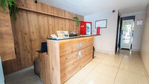A reception desk with a wooden finish, a red Coca-Cola refrigerator, and a map on the wall. - Hotel Montana by Bsb Inn (Nucleo Bandeirante)