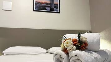 Una habitación de hotel con una cama bien hecha, un ramo de flores y un cuadro en la pared.