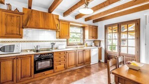 Una cocina con armarios de madera, microondas, estufa y una mesa de comedor con sillas.