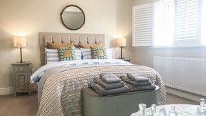 Un dormitorio con cama, lámparas de noche, un espejo redondo, un radiador y un tablero de ajedrez.