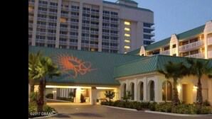 A hotel with a large building featuring a distinctive orange logo, a covered walkway, and multiple balconies.