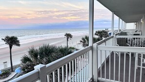 A balcony with a view of the beach and ocean.