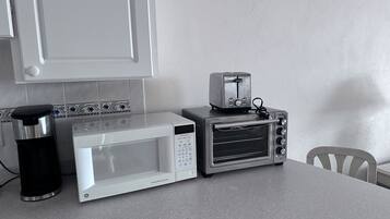 Una cocina con microondas, tostadora y cafetera sobre una encimera.