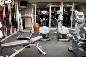 A gym with treadmills, elliptical machines, and a bench. - Josh’s Daytona Beach Resort 1BR Oceanfront Condo 🏖 (Daytona Beach)