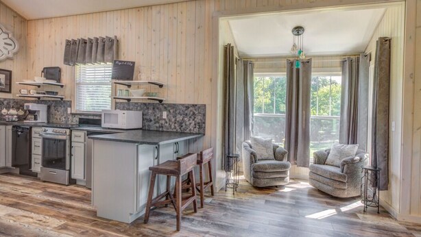 Une cuisine moderne dotée d’un îlot central, de planchers en bois et d’un coin repas avec deux chaises.
