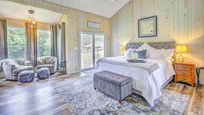 Ein geräumiges Schlafzimmer mit einem großen Bett, zwei Sesseln, einer Bank und Holzboden.