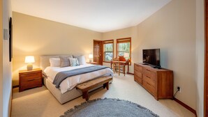 Een slaapkamer met een bed, nachtkastjes, een bureau, een stoel, een televisie en een raam.