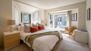 A bedroom with a large bed, bedside tables, a chair, and a window. - Prime Central Location | 5BR | Walk to Village/Lifts | Free Parking | Managed by Aloha Whistler (Whistler)