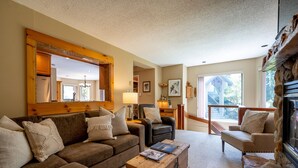 A cozy living room with a brown sofa, a wooden coffee table, and a stone fireplace. - Prime Central Location | 5BR | Walk to Village/Lifts | Free Parking | Managed by Aloha Whistler (Whistler)