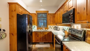 Una cocina con armarios de madera, un refrigerador de acero inoxidable, un microondas y una estufa.