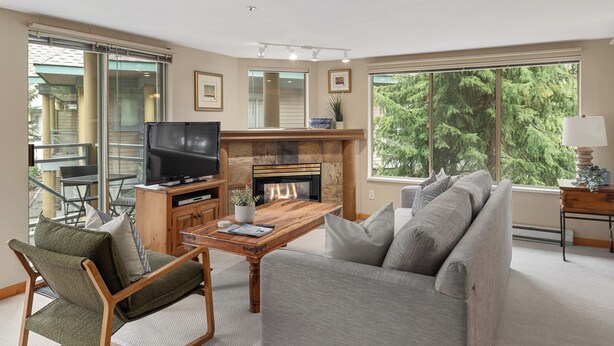 A living room with a fireplace, a television, a sofa, and a dining table.