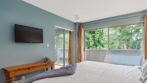 A bedroom with a bed, a TV mounted on the wall, and a sliding glass door leading to a balcony.