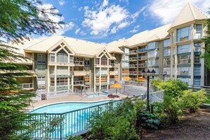 A hotel with a swimming pool, outdoor seating, and a landscaped garden.