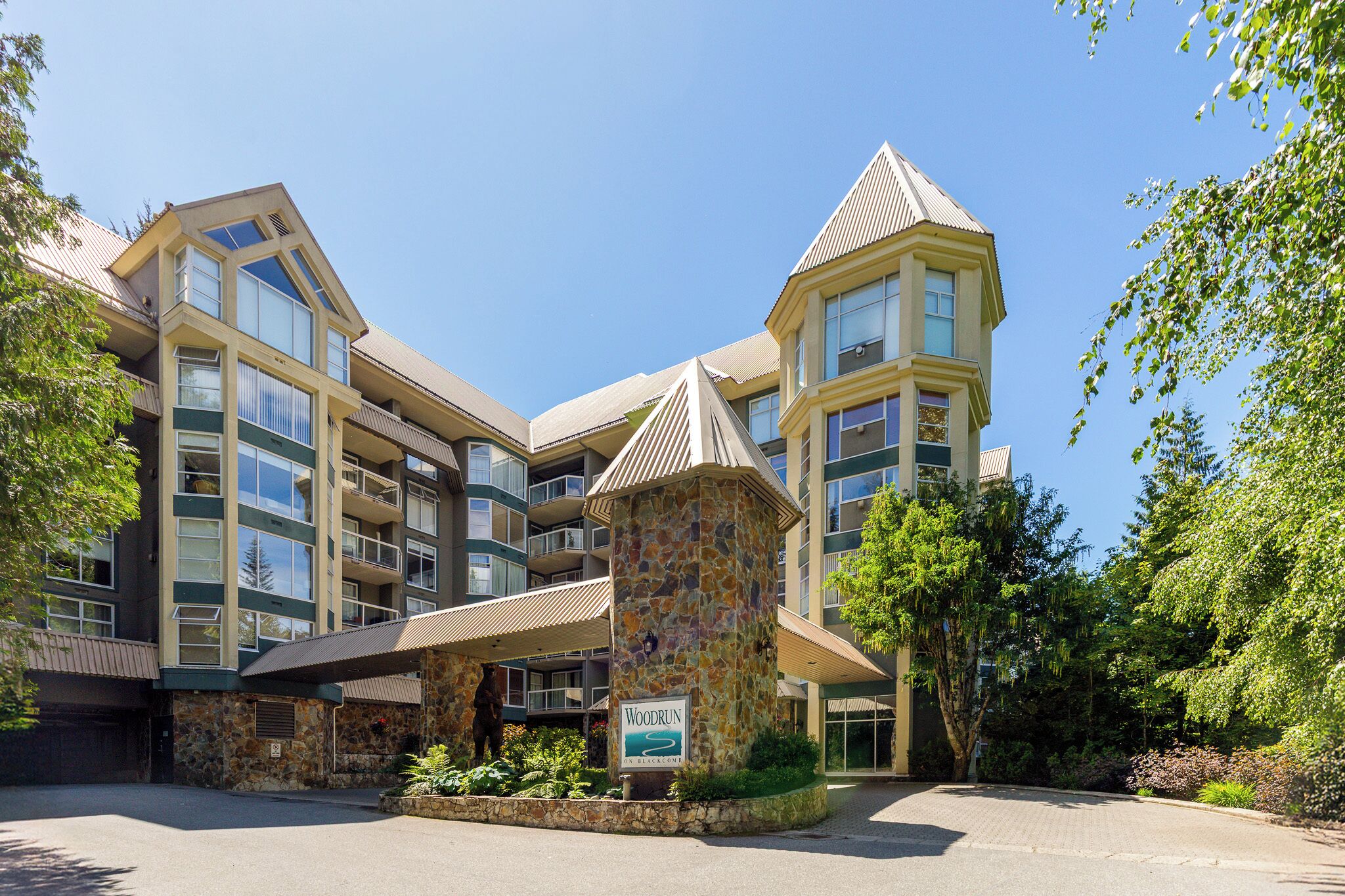 Ein mehrstöckiges Hotel mit einer Stein-Fassade, Balkonen und einem Schild mit der Aufschrift 'Woodrun on Blackcomb'.