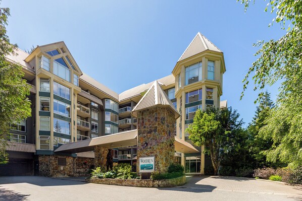 A multi-story hotel with a stone facade, balconies, and a sign indicating 'Woodrun on Blackcomb.'