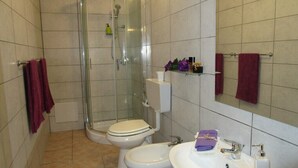 A bathroom with a glass shower enclosure, two toilets, a sink, and a mirror. - Villa Ingeborg King Room (QUARTU SANT'ELENA)