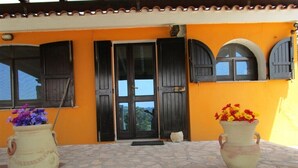 A building with a yellow facade, black shutters, and a stone-paved entrance. - Villa Ingeborg King Room (QUARTU SANT'ELENA)