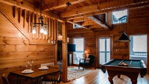 Un intérieur en bois comprenant une table de billard, une table à manger et des chaises.