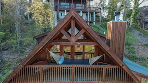 Une cabane en bois dotée d’un balcon, d’un hamac et d’une terrasse.