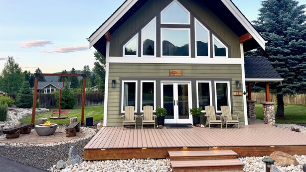Ein zweistöckiges Haus mit einer Terrasse, großen Fenstern und einem Schild mit der Aufschrift 'Cascade Chalet'.