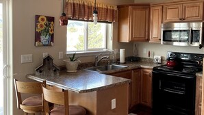 A kitchen with wooden cabinets, a granite countertop, a black stove, and a large island with bar stools.