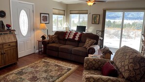A cozy living room with a brown sofa, patterned armchair, and a wooden cabinet.