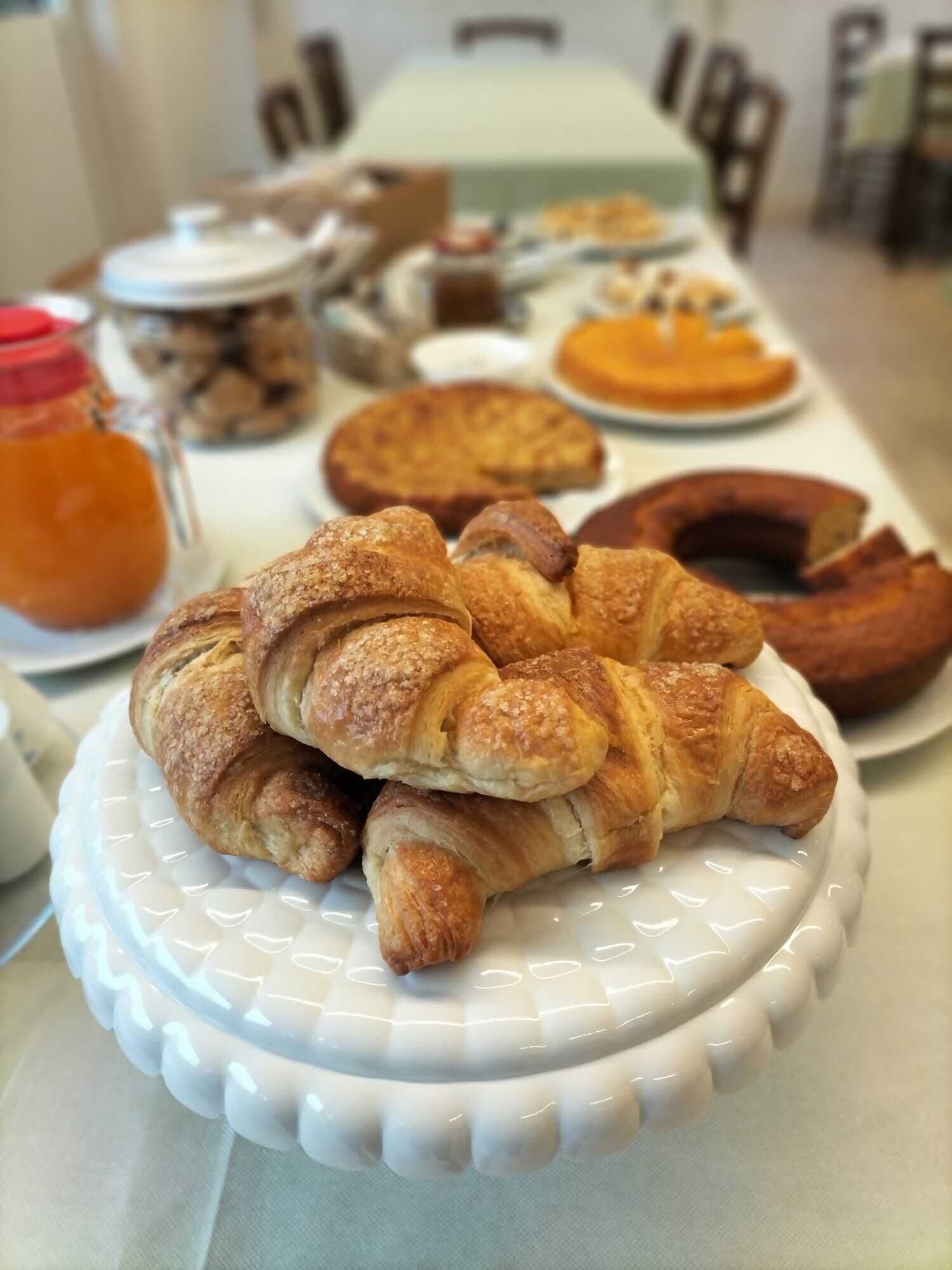 Ein Tisch mit verschiedenen Backwaren, darunter Croissants und ein Kuchen.