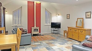 A living room with a TV, wooden furniture, a red accent wall, and a fireplace.