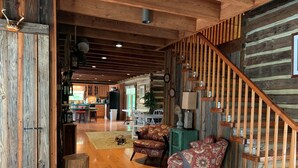 A spacious living area with a wooden floor, a staircase with a wooden railing, and a dog resting on a rug.