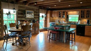 A rustic kitchen with wooden cabinets, a large island with stools, and a dining area with a table and chairs.