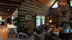 A cozy log cabin interior with a fireplace, leather furniture, and a dining area.