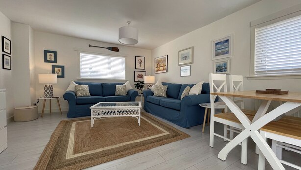 A modern living room with a blue sofa set, a white coffee table, and a dining table with chairs. - A beautiful coastal cottage in characterful Portmahomack. (Portmahomack, near Dornoch)