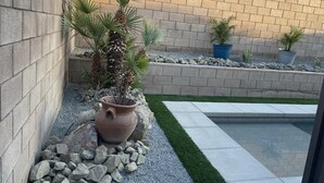 A landscaped garden with a variety of plants, a large terracotta pot, and a small pool. - Desert Oasis salt water Pool/spaHome, Gated Community w/LAKE (Indio)