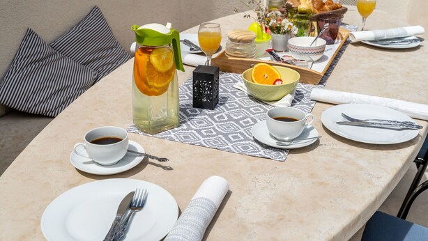 A table set for breakfast with a pitcher of orange juice, a cup of coffee, and a tray of pastries. - Lorena Suite - Two Bedroom Apartment with Private Pool (Dubrovnik)
