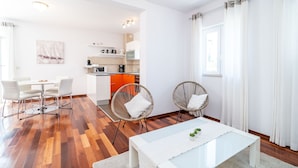 A modern living room with a dining area, kitchen, and two wicker chairs. - Lorena Suite - Two Bedroom Apartment with Private Pool (Dubrovnik)