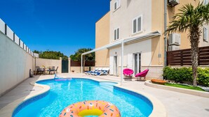 A swimming pool with a donut float, lounge chairs, and a patio area. - Lorena Suite - Two Bedroom Apartment with Private Pool (Dubrovnik)