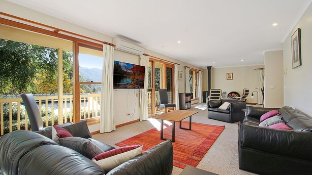 A spacious living room with a large window, a fireplace, and a balcony with a view of the outdoors. - Greenlea (BRIGHT)