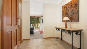 A hallway with a wooden door, a table with a lamp, and a painting on the wall. - Greenlea (BRIGHT)