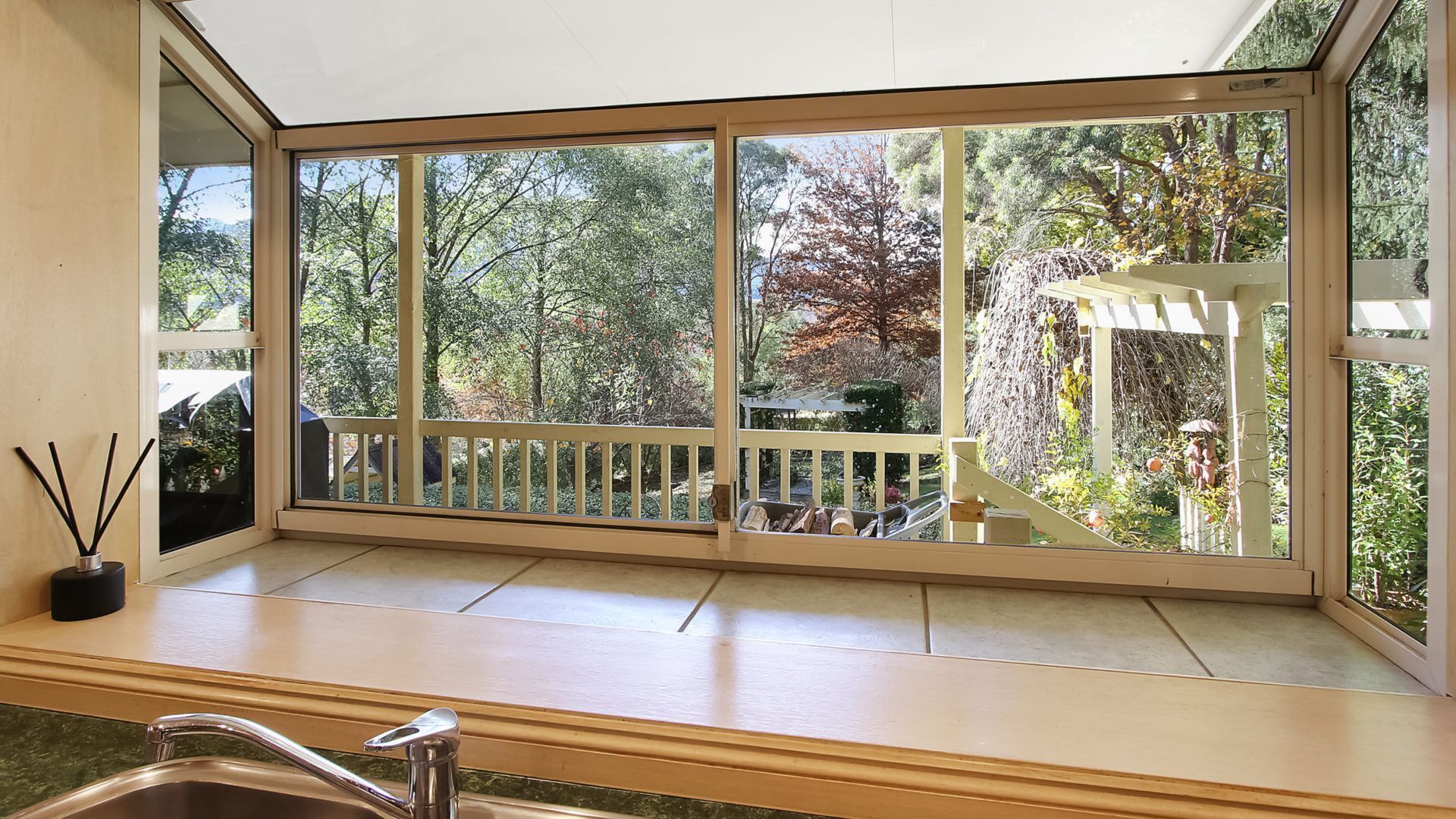A kitchen with a large window overlooking a garden.