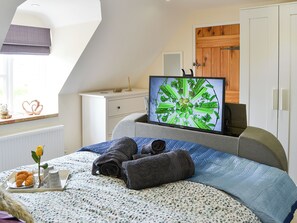 A bedroom with a bed, a television, a dresser, a window, and a door. - Stepping Stone Cottage (Bacton, near North Walsham)