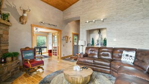 A spacious living room with a leather sofa, a wooden coffee table, and a mounted deer head. - Beautiful Rustic Mountain Home (Durango)
