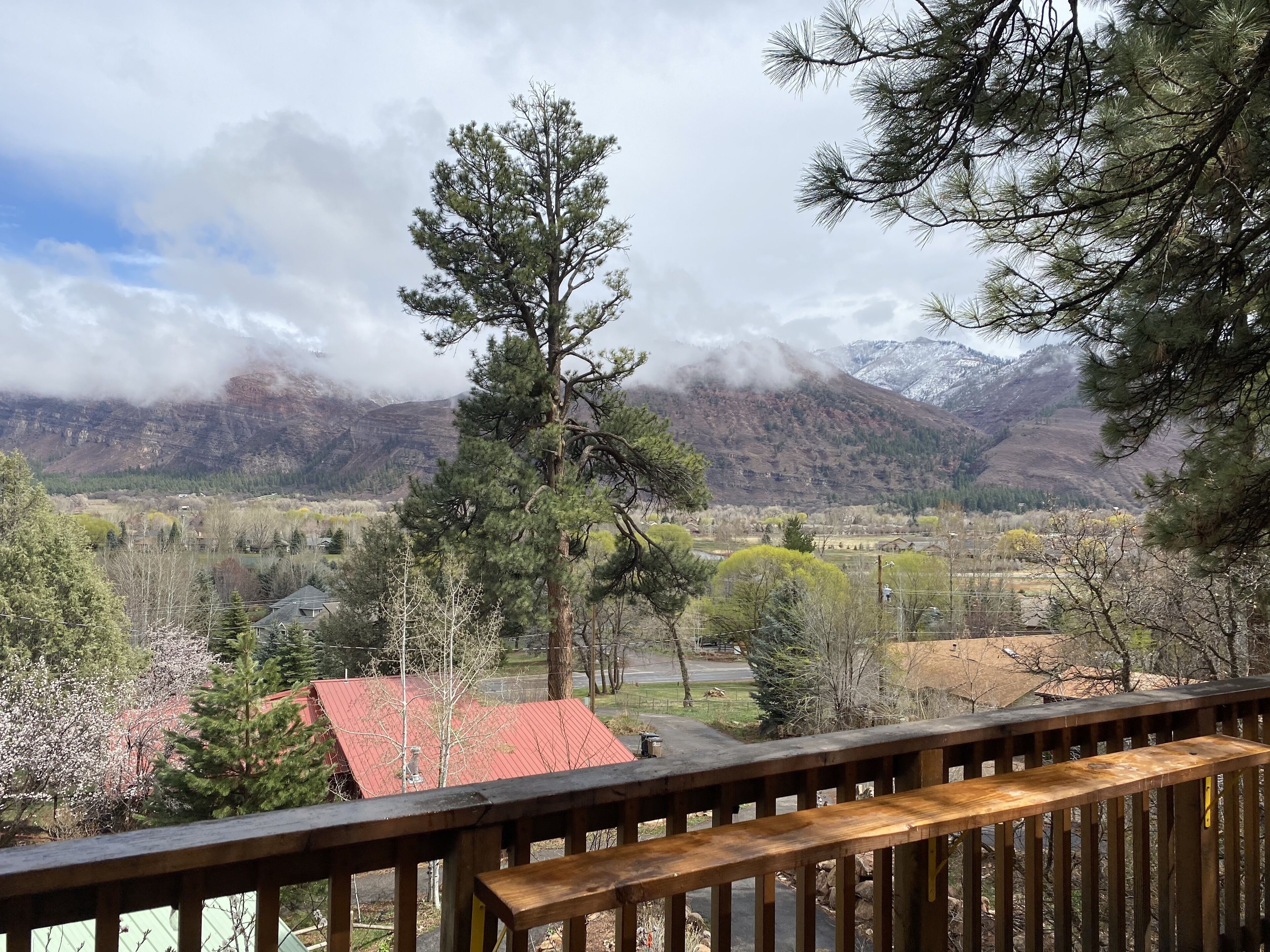 A mountain landscape with a wooden deck and a red-roofed building in the foreground.