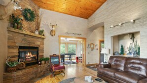 A spacious living room with a stone fireplace, leather sofa, and a wooden coffee table. - Beautiful Rustic Mountain Home (Durango)