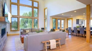 A spacious living room with a large gray sofa, wooden flooring, and a stone fireplace. - The Ledges | Ski Getaway | Hot Tub & Theater Room (Eden)