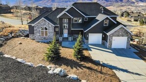 A two-story house with a stone facade, a garage, and a driveway. - The Ledges | Ski Getaway | Hot Tub & Theater Room (Eden)
