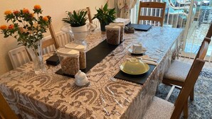 A dining table set with a lace tablecloth, various dishes, and a vase with flowers. - Professional Bed & Breakfast en-suite double rooms £80 per night per room. (Warwick)