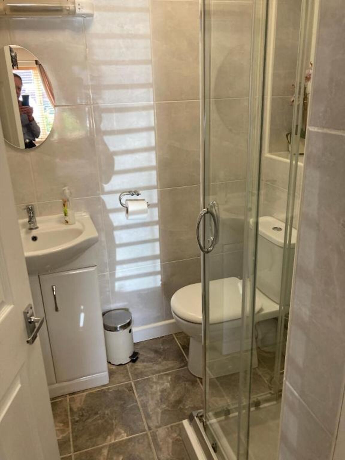 Een badkamer met een douchecabine van glas, een wastafel met spiegel en een toilet.