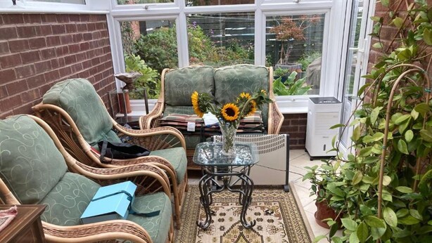 A sunroom with wicker furniture, a patterned rug, and a view of the garden through large windows. - Professional Bed & Breakfast en-suite double rooms £80 per night per room. (Warwick)