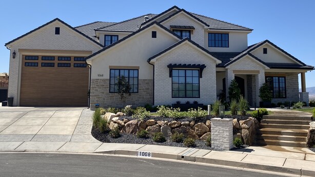 A modern two-story house with a garage, large windows, and a stone facade.