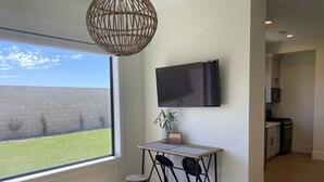 A modern kitchen with a flat-screen TV, a small table with chairs, and a view of the outside.